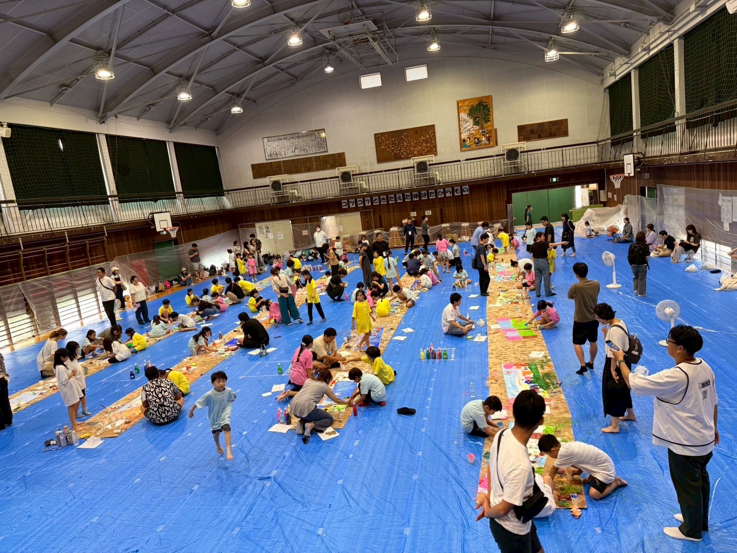 子どもたちが体育館で絵を描く様子